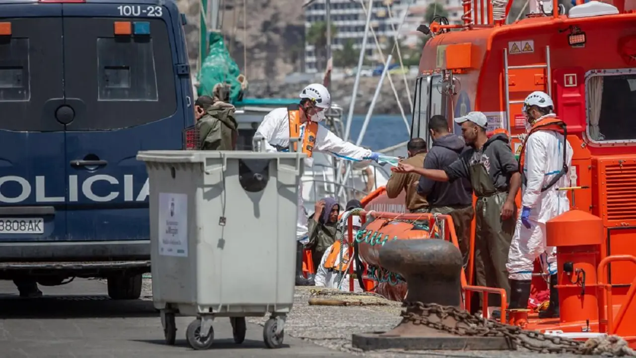 Agentes de la Policía Nacional española entregan máscaras faciales a las personas que desembarcan de un barco después de que varias embarcaciones de migrantes con un total de 18 personas fueran rescatadas frente a la costa de la isla canaria española de Gran Canaria el 14 de septiembre de 2020 - PHOTO/AFP/DESIREE MARTIN