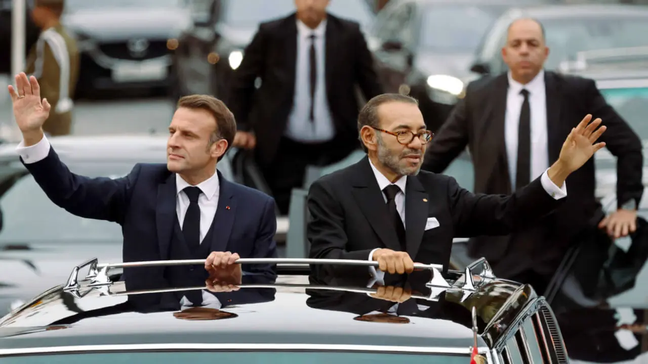 El rey de Marruecos, Mohamed VI, y el presidente de Francia, Emmanuel Macron saludan a la multitud mientras recorren las calles de la capital, Rabat, el 28 de octubre de 2024 - PHOTO/ LUDOVIC MARIN / POOL / AFP