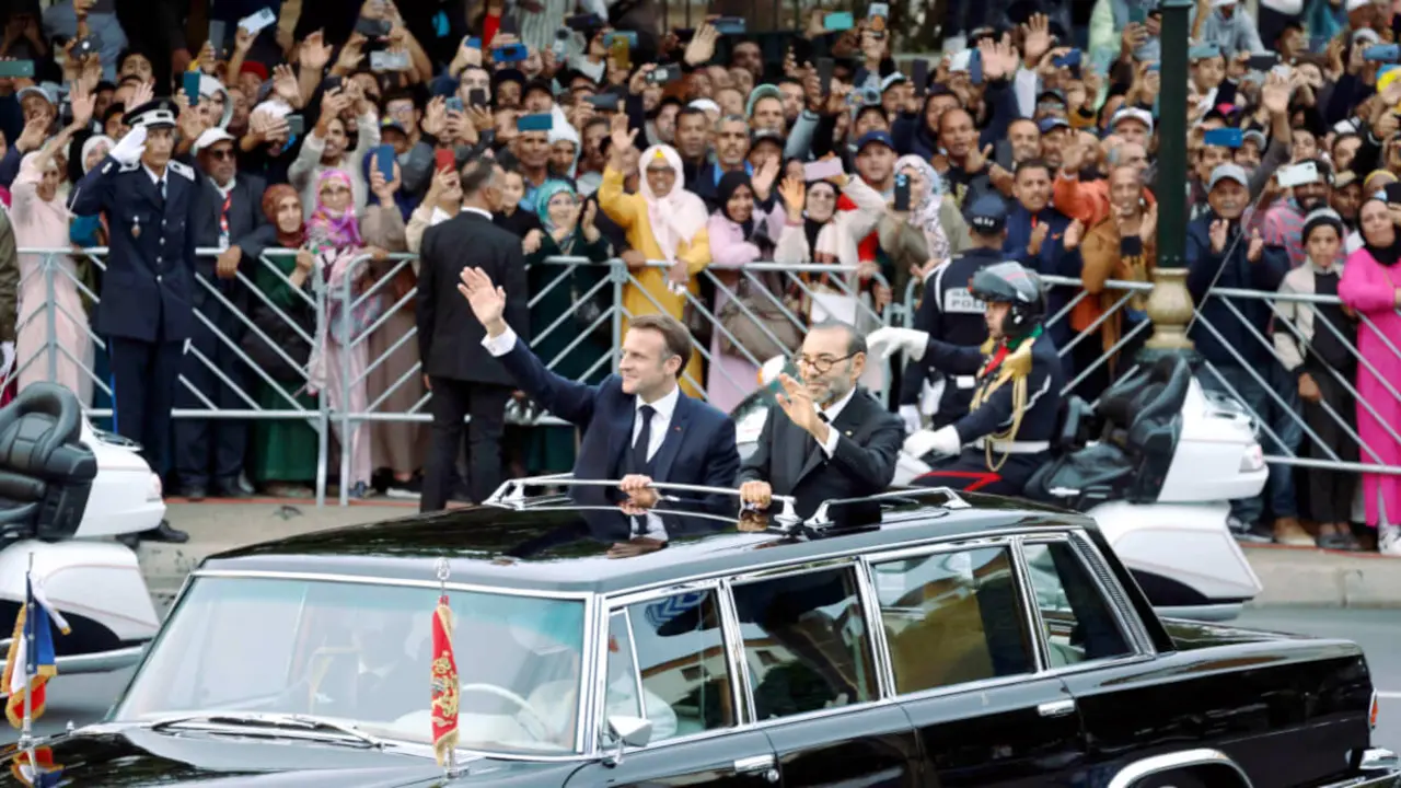 El rey de Marruecos, Mohamed VI, y el presidente de Francia, Emmanuel Macron saludan a la multitud mientras recorren una carretera de la capital, Rabat, el 28 de octubre de 2024 - PHOTO/ LUDOVIC MARIN / POOL / AFP