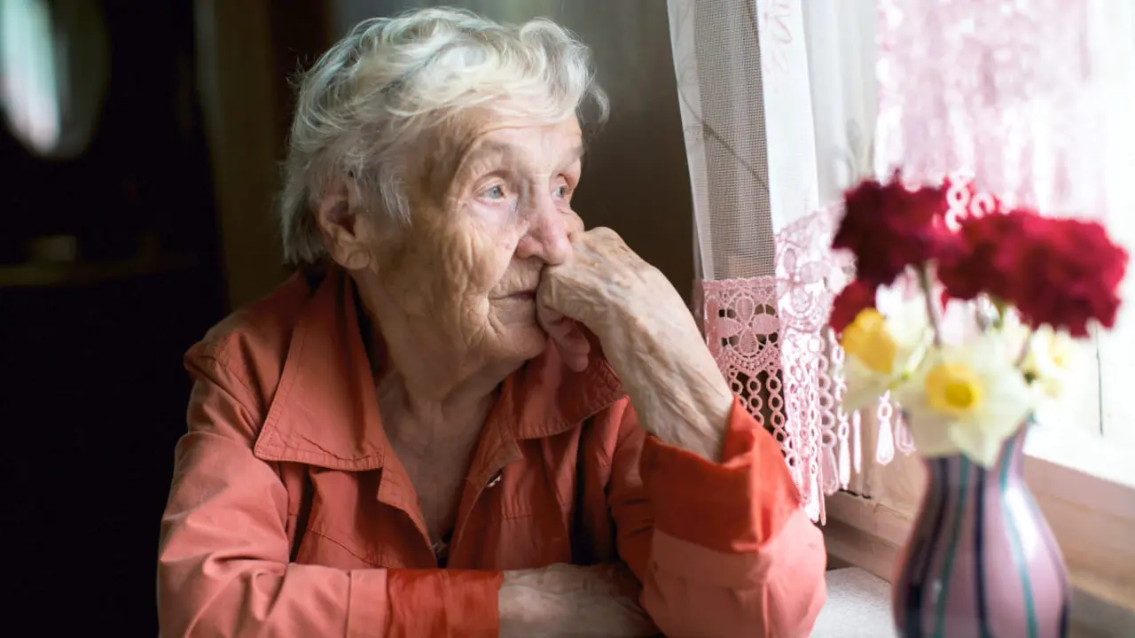Mujer mayor mirando por la ventana - PHOTO/Shutterstock / De Visu