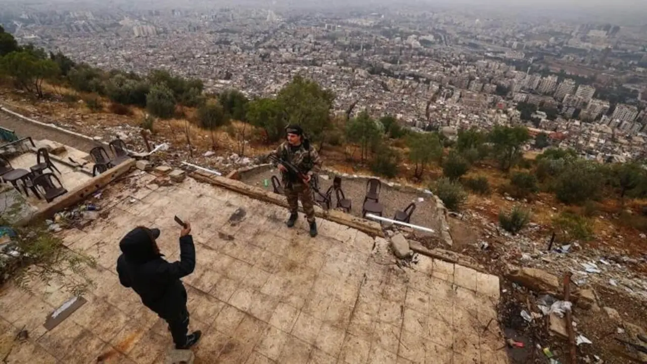 Un combatiente fotografía a su compañero mientras visitan el monte Qasioun, en Damasco, Siria 29 de diciembre de 2024 - PHOTO/REUTERS