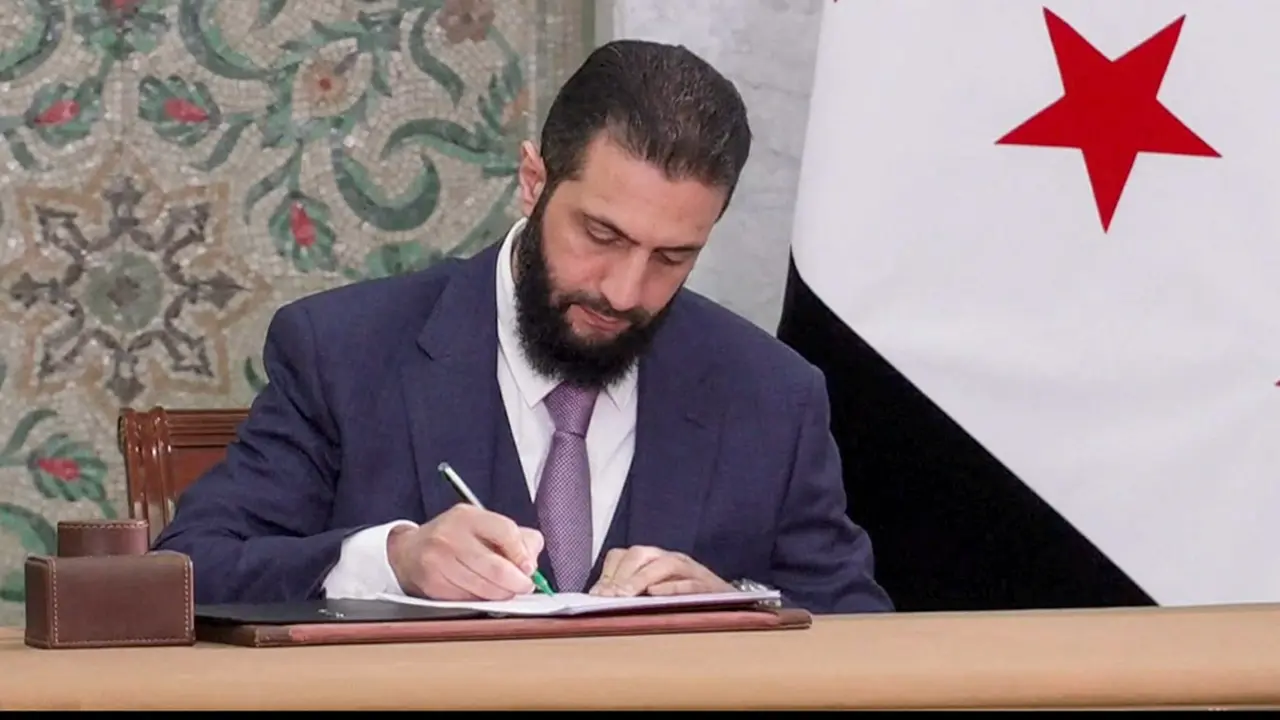 El presidente interino sirio, Ahmed Al-Sharaa, firma un borrador de constitución, tras ser presentado por un comité sirio de expertos legales, en Damasco, Siria, el 13 de marzo de 2025 - PHOTO/ Presidencia siria vía REUTERS TV