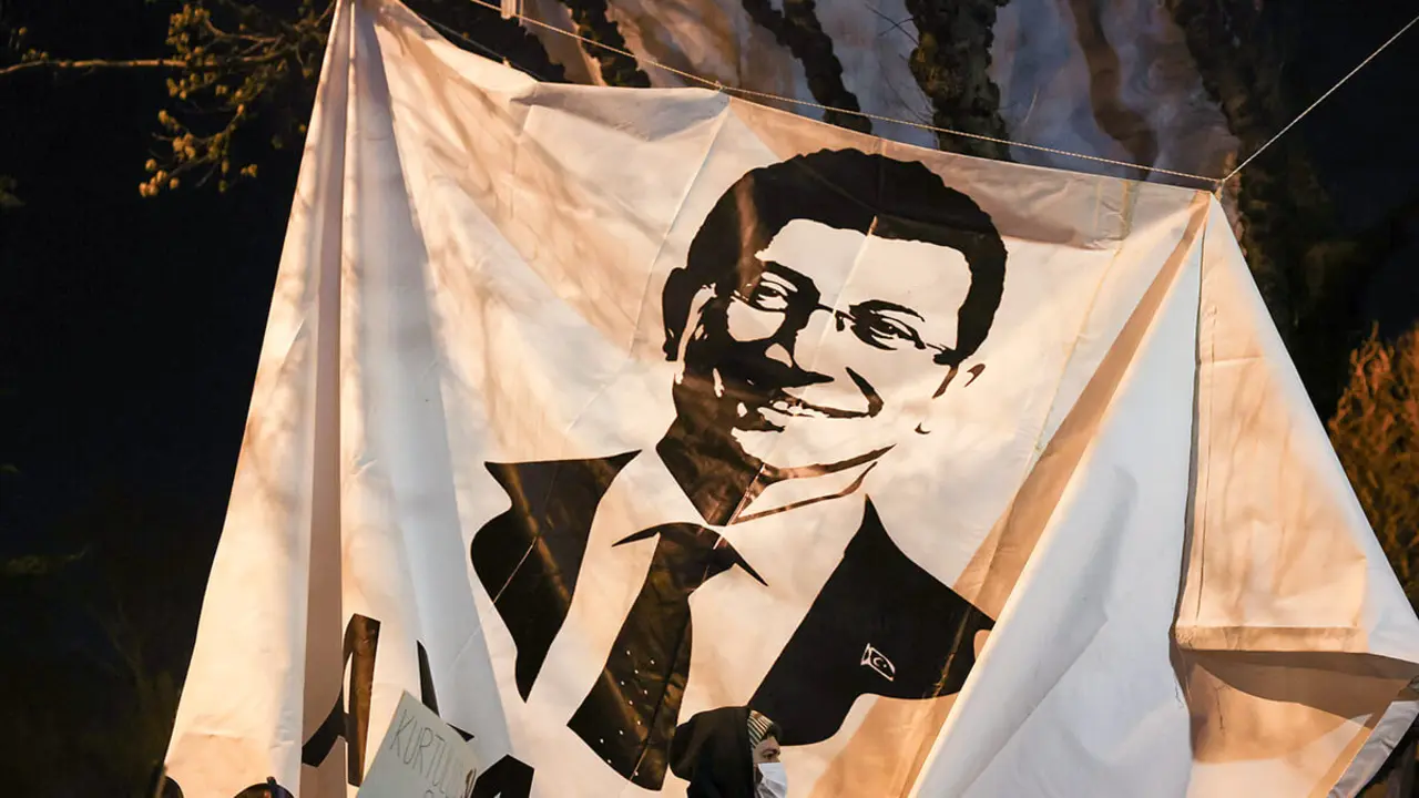 <p>Una persona pasa junto a una pancarta con la imagen del alcalde de Estambul, Ekrem Imamoglu, mientras la gente participa en una protesta contra la detención de Imamoglu, en Estambul, Turquía, el 20 de marzo de 2025 - REUTERS/UMIT BEKTAS&nbsp;</p>
