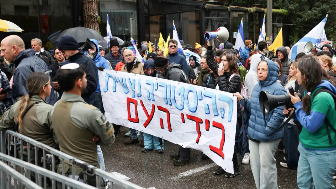 Manifestantes sostienen una pancarta que dice "La historia la hace el pueblo" durante una protesta contra el gobierno israelí y el primer ministro israelí, Benjamin Netanyahu, y exigen la liberación de todos los rehenes de Gaza, cerca de la residencia del primer ministro Netanyahu en Jerusalén, el 21 de marzo de 2025 -&nbsp;REUTERS/ RONEN ZVULUN