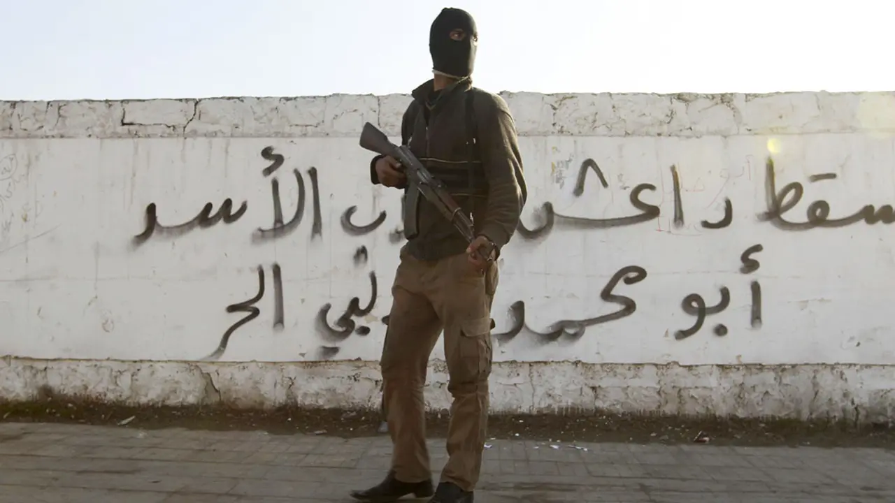 Un combatiente del Ej&eacute;rcito Libre Sirio porta su arma frente a un grafiti con la leyenda Daesh en el barrio de Masaken Hanano, Alepo - REUTERS//JALAL ALHALABI
