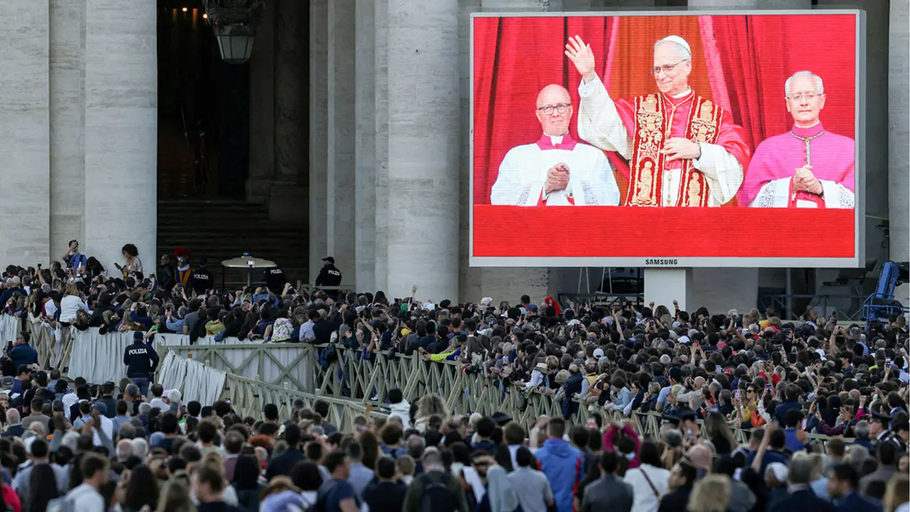 La gente observa mientras el recién elegido papa León XIV, el cardenal Robert Prevost de Estados Unidos, que aparece en la pantalla, aparece en el balcón de la Basílica de San Pedro, visto desde Roma, Italia, el 8 de mayo de 2025 - REUTERS/ ALKIS KONSTANTINIDIS