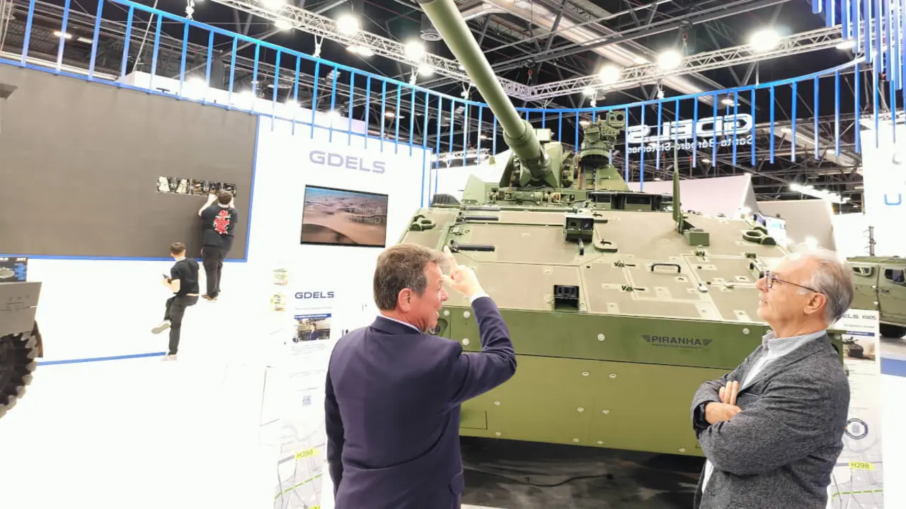 <p>El máximo responsable de GDELS-SB, Juan Escriña (izquierda), explica a un visitante las grandes prestaciones del obús autopropulsados Piranha de tracción 10x10 durante su exhibición en FEINDEF 25 -&nbsp;PHOTO/JPons&nbsp;</p>
