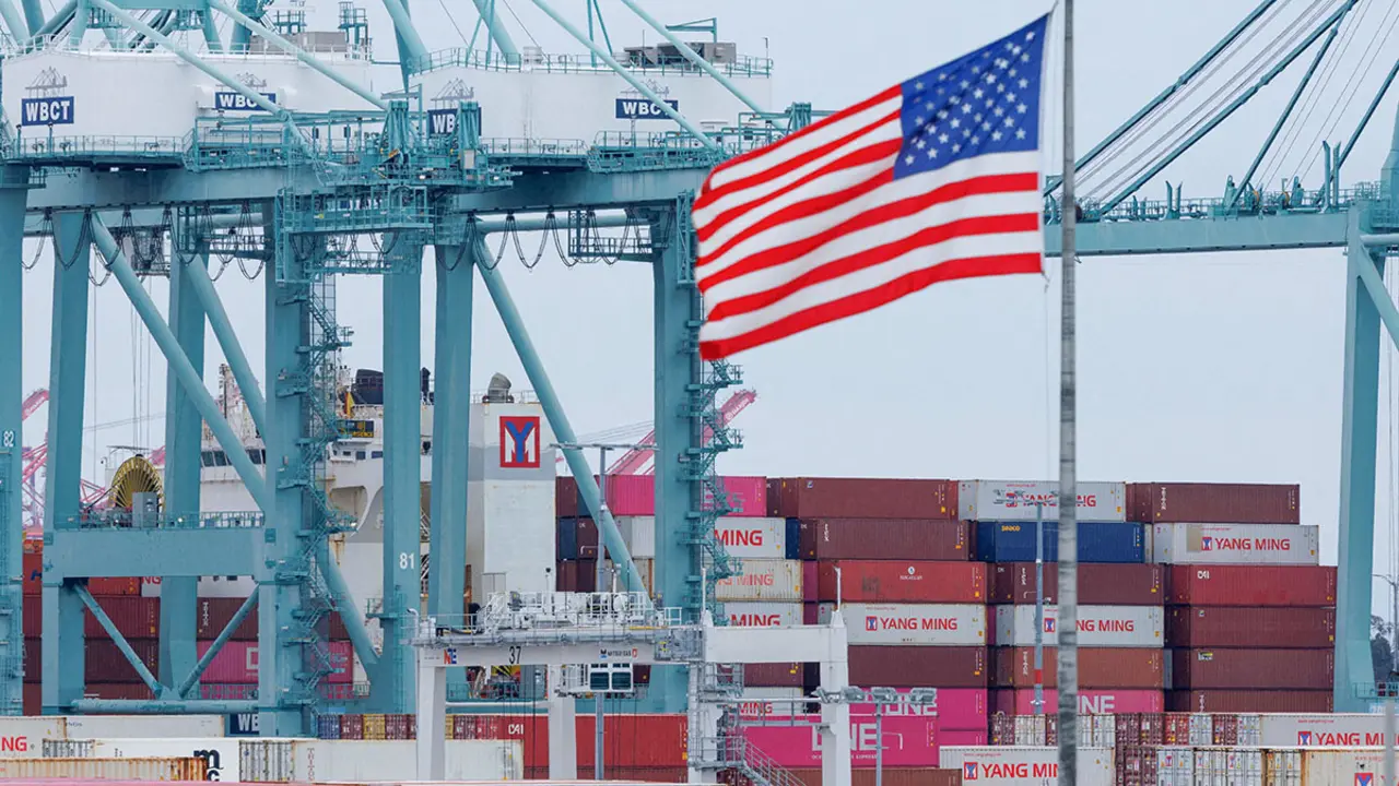 Una bandera estadounidense ondea cerca de contenedores mientras se descarga un barco en el Puerto de Los Ángeles, en San Pedro, California, EE. UU., el 1 de mayo de 2025 - REUTERS/ MIKE BLAKE