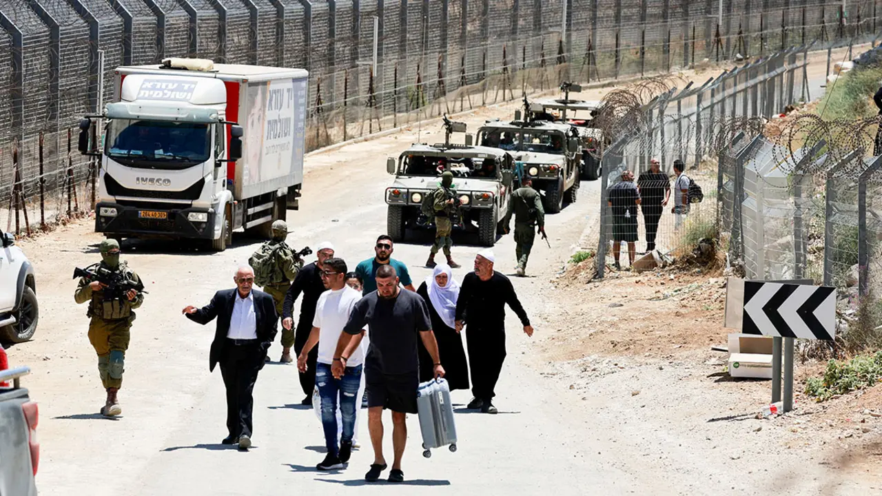 <p>El Ejército israelí escolta a sirios mientras caminan desde Majdal Shams de regreso a Siria, a lo largo de la línea de alto el fuego entre los Altos del Golán ocupados por Israel y Siria, en medio del conflicto en curso en las zonas drusas de Siria, en Majdal Shams, el 17 de julio de 2025 - REUTERS/ AMMAR AWAD&nbsp;</p>

