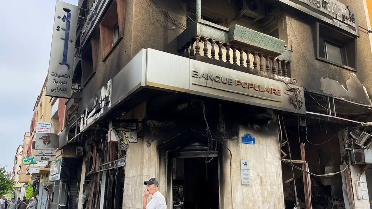 <p>Un hombre permanece junto a un edificio incendiado que albergaba un banco, tras las protestas antigubernamentales lideradas por j&oacute;venes, en Sale, Marruecos, el 2 de octubre de 2025 - REUTERS/ AHMED EL JECHTIMI&nbsp;</p>
