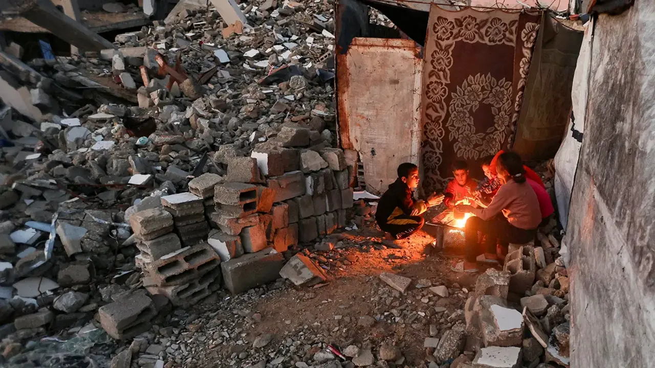 <p>Ni&ntilde;os palestinos calientan sus manos sobre el fuego en un d&iacute;a lluvioso en Khan Younis, al sur de la Franja de Gaza, el 25 de noviembre de 2025 - REUTERS/ RAMADAN ABED</p>
