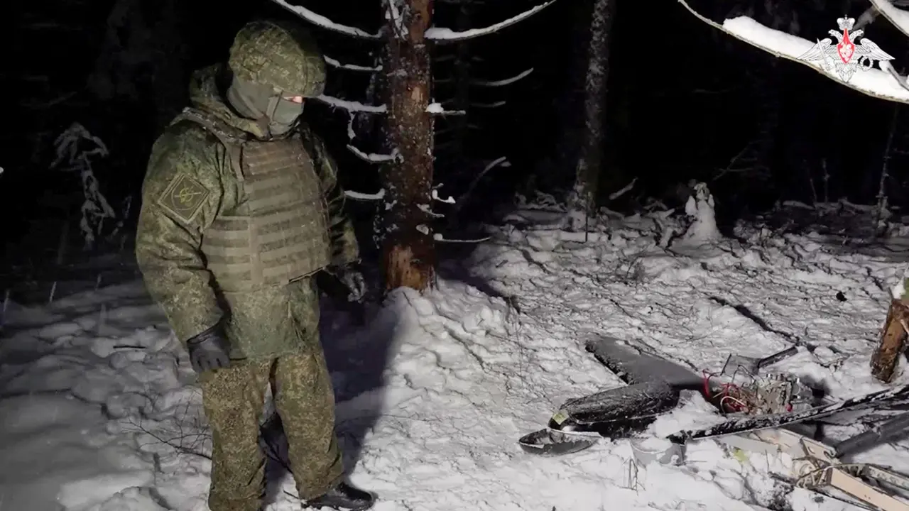 Un miembro del ej&eacute;rcito ruso junto a los restos de un dron que, seg&uacute;n el Ministerio de Defensa ruso, fue derribado durante la repulsi&oacute;n de un supuesto ataque ucraniano contra la residencia presidencial rusa en la regi&oacute;n de N&oacute;vgorod, en una ubicaci&oacute;n desconocida de Rusia, en esta imagen fija de un v&iacute;deo publicado el 31 de diciembre de 2025 - Ministerio de Defensa ruso via REUTERS