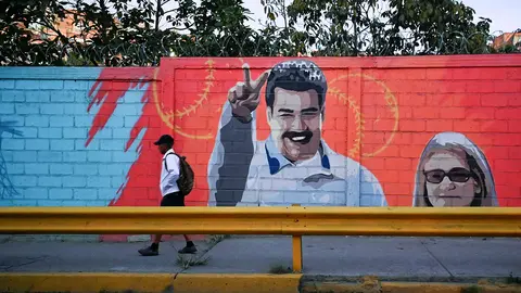 Un hombre pasa junto a un mural que muestra al presidente de Venezuela, Nicolás Maduro, y a su esposa,&nbsp;Cilia&nbsp;Flores, en Caracas, Venezuela, el 3 de enero de 2026 - REUTERS/MAXWELL BRICEÑO
