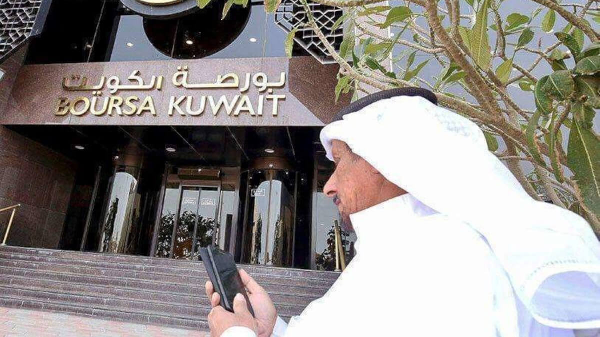 AFP/ YASSER AL-ZAYYAT - Un hombre revisa su teléfono frente a la entrada de la Bolsa de Kuwait