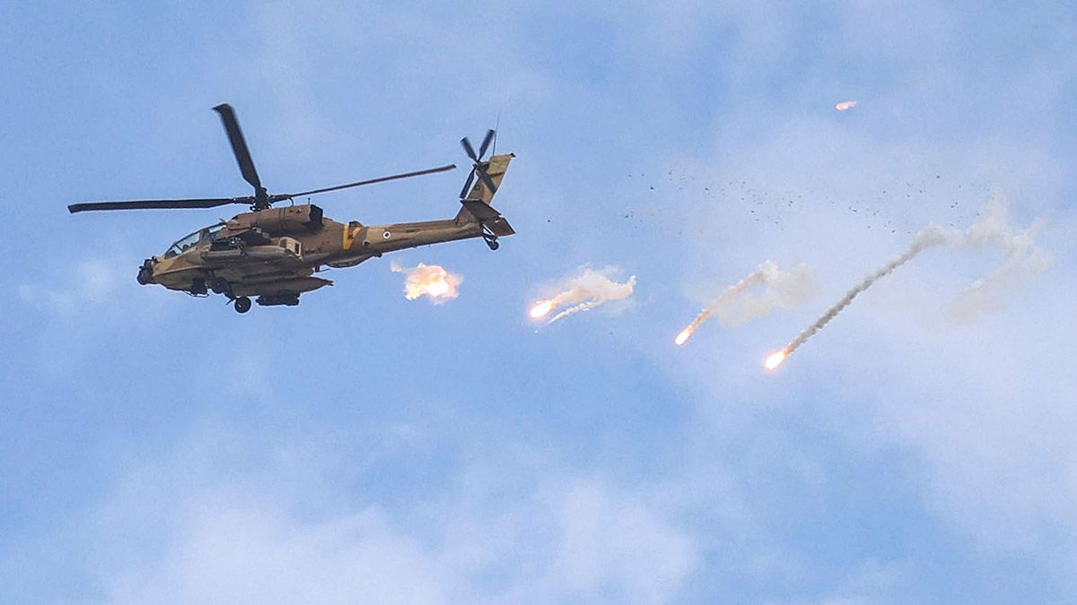 An Israeli Air Force AH-64 Apache attack helicopter releases a payload during an Israeli army raid in Jenin in the occupied West Bank on June 19, 2023. Violent clashes erupted in Jenin on June 19 during an Israeli raid on the West Bank city in which the army fired missiles from a helicopter, according to an AFP photographer at the scene. (Photo by Jaafar ASHTIYEH / AFP)