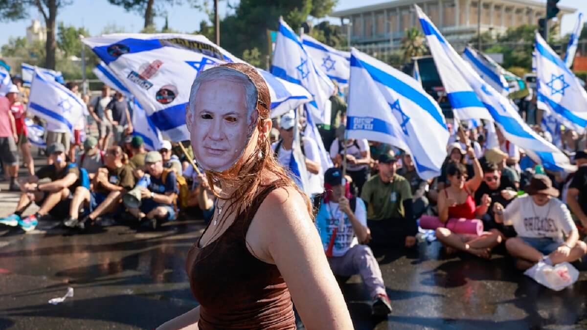 PHOTO/AFP/MENAHEM KAHANA - Una manifestante con una máscara que representa al primer ministro de Israel, Benjamin Netanyahu