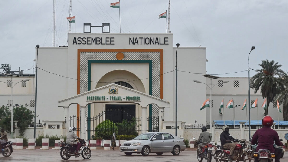 PHOTO/AFP - Varios automovilistas pasan por delante de la Asamblea Nacional en Niamey el 7 de agosto de 2023, los gobernantes militares de Níger desafiaron el lunes un ultimátum para restaurar el Gobierno electo