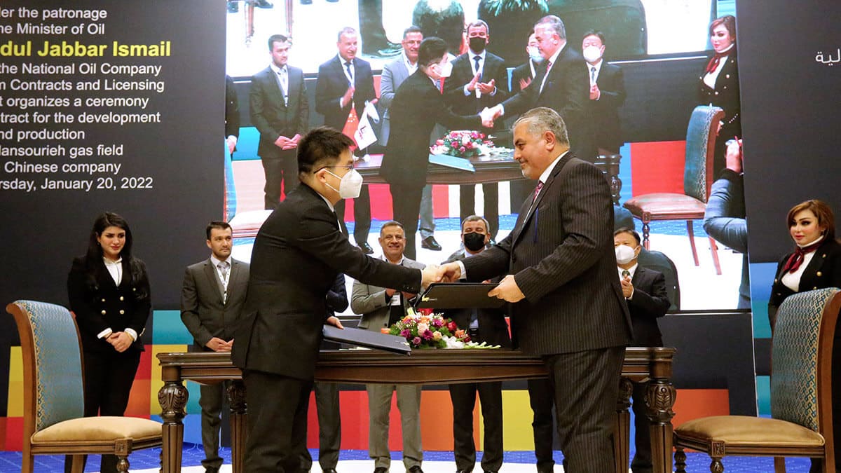 AFP/SABAH ARAR - Ali Maarij (R), director de Contratos y Licencias del Ministerio de Petróleo iraquí, se da la mano tras la firma de la licencia para el campo de gas de Mansouriya, en la gobernación de Diyala, con la empresa china Sino-Pec. en Bagdad el 20 de enero de 2022
