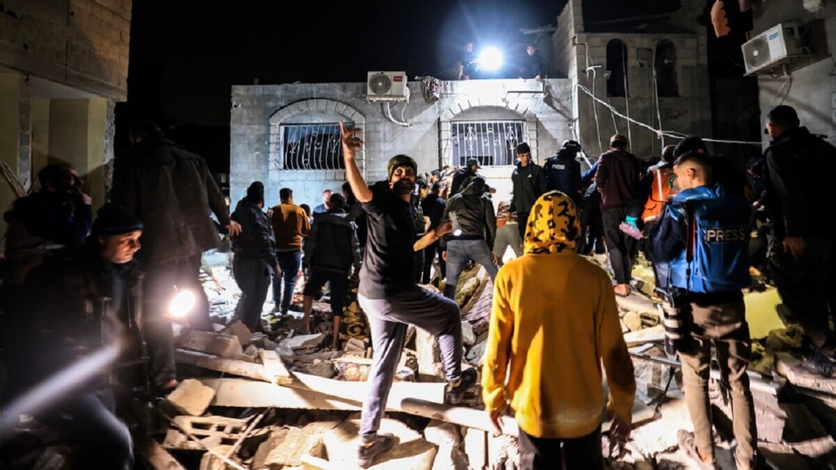 Varias personas se reúnen frente a un edificio alcanzado por un ataque israelí en Rafah, en el sur de la franja de Gaza, el 28 de diciembre de 2023, mientras continúan los combates entre Israel y el movimiento palestino Hamás – PHOTO/Mahmud HAMS/AFP