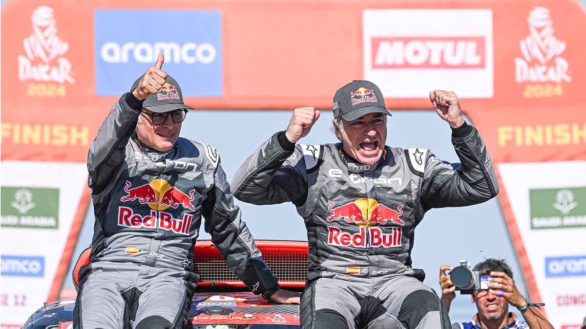 El piloto español Carlos Sainz (R) y su copiloto español Lucas Cruzof (L) celebran en su coche tras cruzar la línea de meta de la etapa 12 del rally Dakar 2024 desde Yanbu a Yanbu, el 19 de enero de 2024 (AFP/PATRICK HERTZOG)