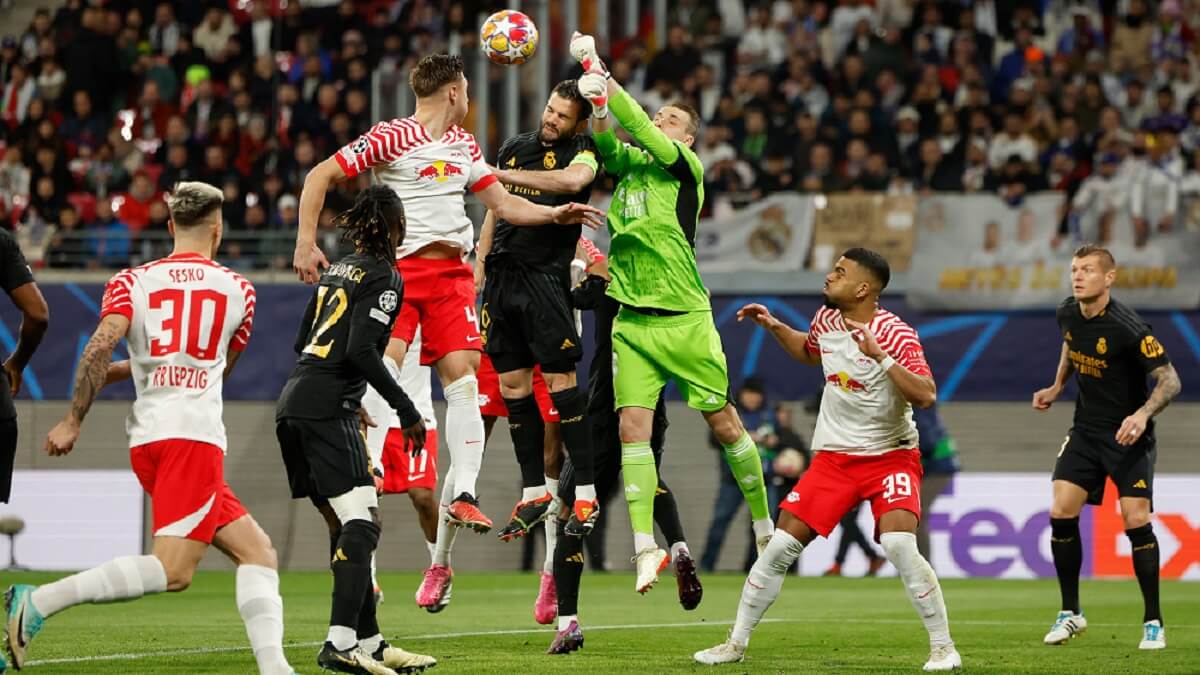 El portero ucraniano del Real Madrid Andriy Lunin golpea el balón junto al defensa español del Real Madrid Nacho Fernández y el defensa húngaro del Leipzig Willi Orban durante el partido de fútbol de ida de octavos de final de la UEFA Champions League entre el RB Leipzig y el Real Madrid CF en Leipzig, Alemania, el 13 de febrero de 2024 – PHOTO/Odd ANDERSEN/AFP