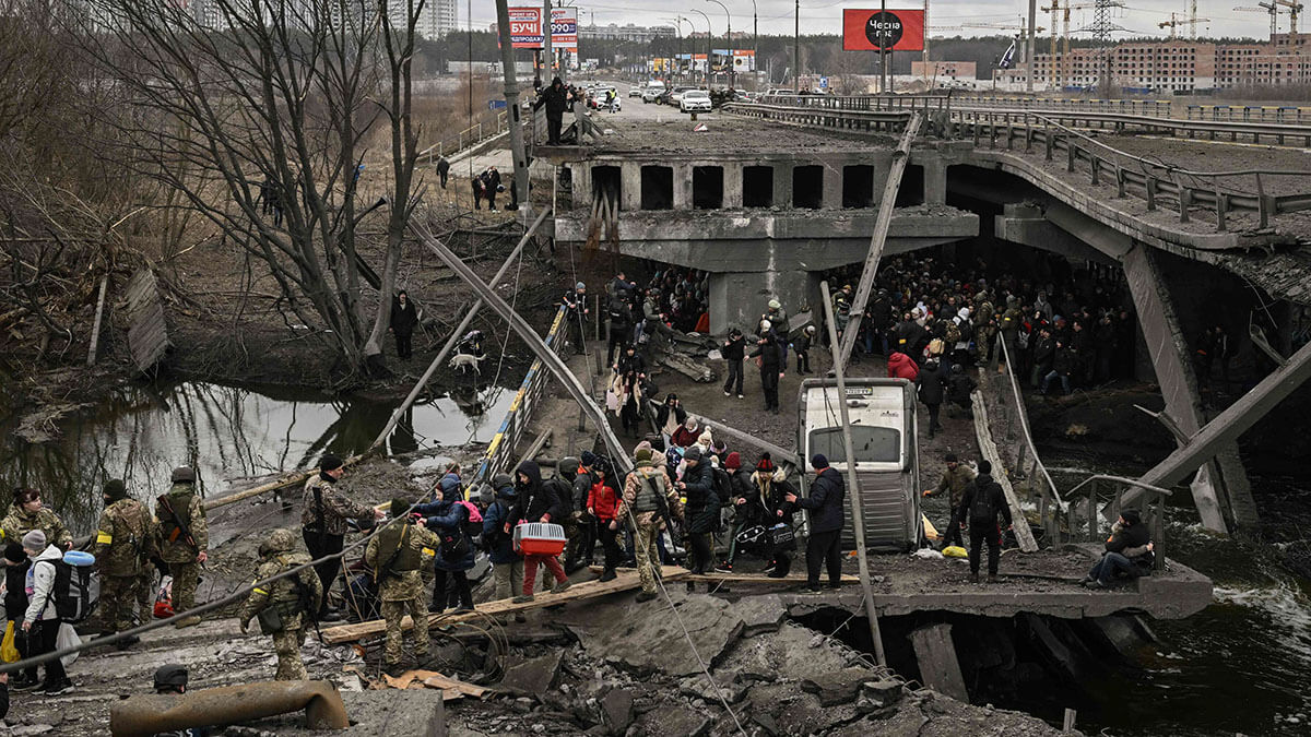 Personas cruzan un puente destruido mientras evacuan la ciudad de Irpin, al noroeste de Kiev, durante fuertes bombardeos y bombardeos el 5 de marzo de 2022 - AFP/ARIS MESSINIS