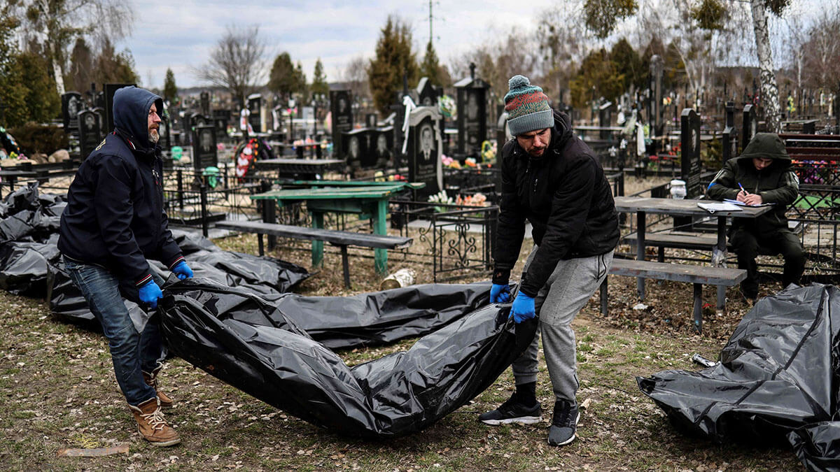 Trabajadores alinean los cuerpos para su identificación por parte del personal forense y agentes de policía en el cementerio de Bucha, al norte de Kiev, el 6 de abril de 2022 - AFP/RONALDO SCHEMIDT
