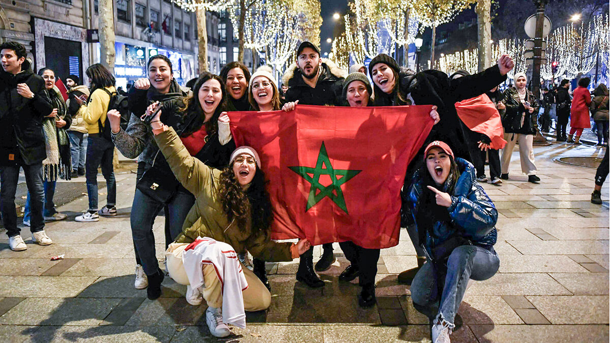 Seguidores de Marruecos aplauden con una bandera nacional mientras celebran la victoria de su selección nacional después del partido de fútbol de la Copa Mundial Qatar 2022 entre Marruecos y España, en los Campos Elíseos de París, el 6 de diciembre de 2022 - AFP/STEPHANE DE SAKUTIN