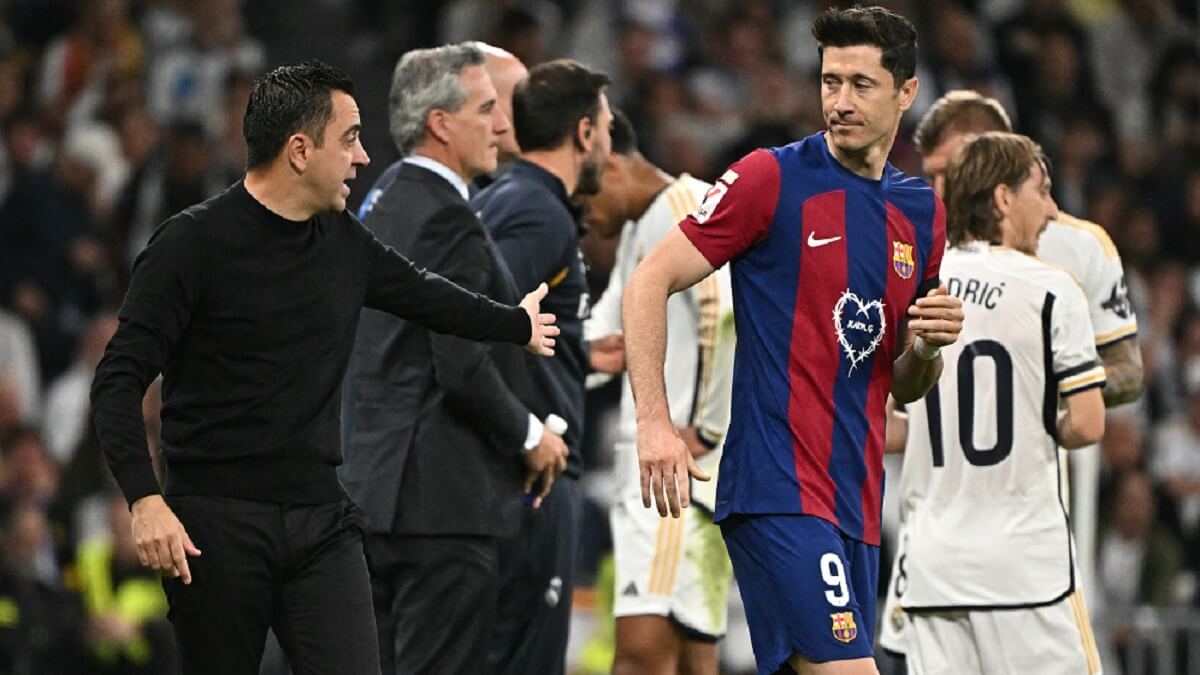 El entrenador español del Barcelona Xavi habla con el delantero polaco del Barcelona Robert Lewandowski durante el partido de fútbol de la Liga española entre el Real Madrid CF y el FC Barcelona en el estadio Santiago Bernabéu de Madrid el 21 de abril de 2024 – PHOTO/JAVIER SORIANO/AFP