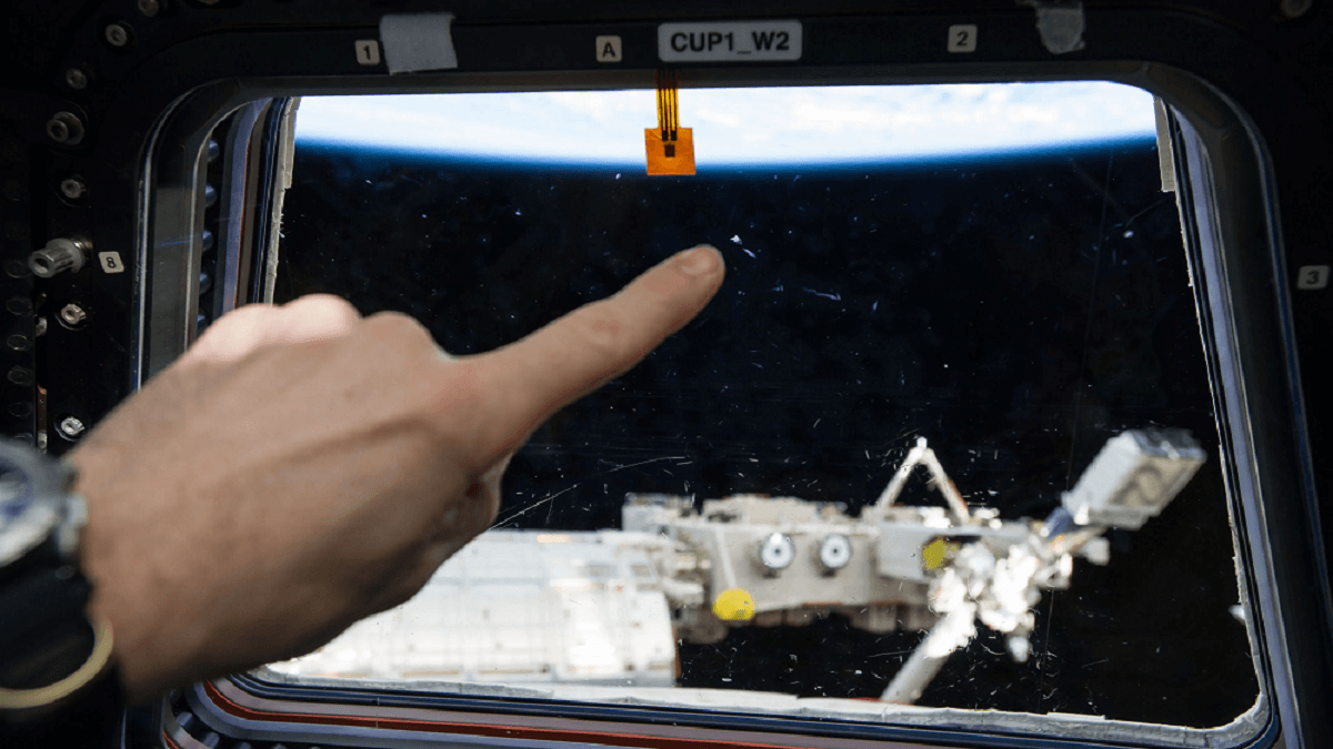 Un astronauta a bordo de la Estación Espacial Internacional señala en lugar de impacto de un minúsculo fragmento, que a la altura del complejo orbital viajan a mucha mayor velocidad que una bala - PHOTO/NASA