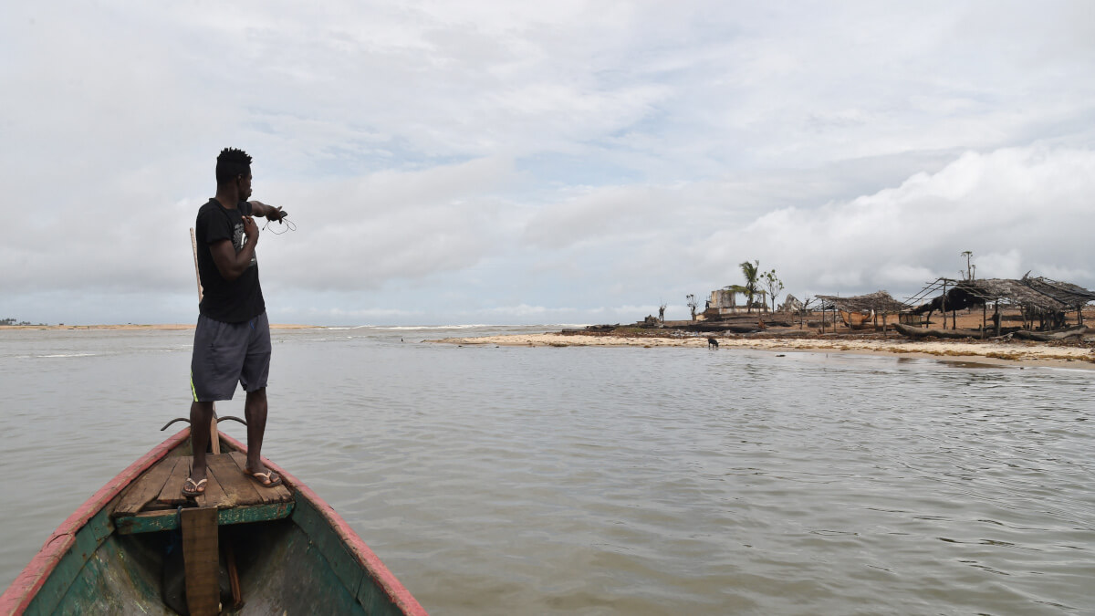 Un residente de pie en un barco señala las ruinas de un hospital en la ciudad marfileña de Grand Lahou, situada donde el río Bandama se encuentra con el Golfo de Guinea - ISSOUF SANOGO / AFP