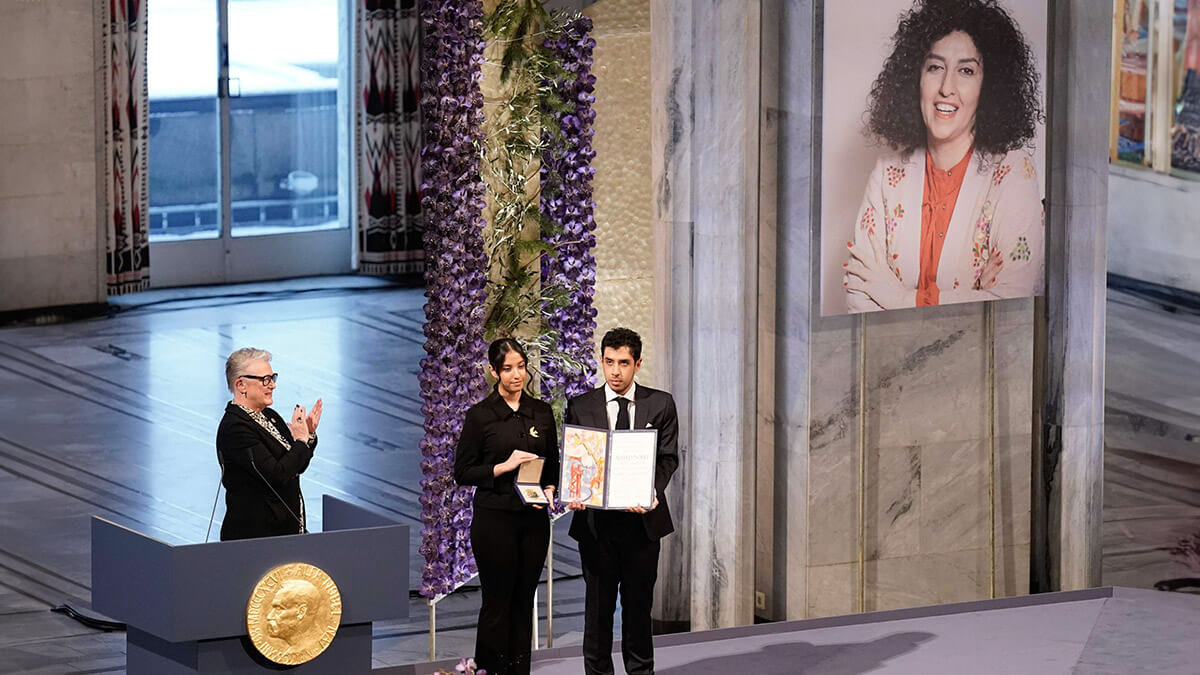 La presidenta del Comité Nobel, Berit Reiss-Andersen (izq.), aplaude mientras Kiana Rahmani y Ali Rahmani posan con el premio en nombre de su madre durante la ceremonia del Premio Nobel de la Paz 2023 en el Ayuntamiento de Oslo el 10 de diciembre, 2023 - REUTERS/FREDRIK VARFJELL