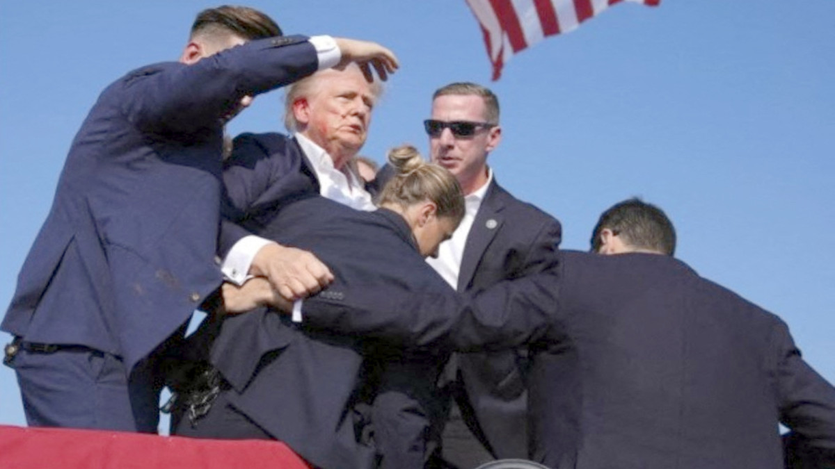 Esta captura de pantalla de video muestra al ex presidente de Estados Unidos, Donald Trump, siendo ayudado a bajar del escenario en un mitin en Butler, Pensilvania, Estados Unidos, después de que lo que sonó como disparos sonara entre la multitud, el 13 de julio de 2024 - PHOTO/Xin Hua/XINHUA/Xinhua via AFP