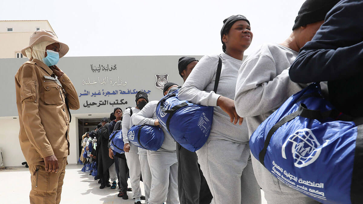 Migrantes irregulares nigerianos hacen cola para subir a los autobuses de la oficina antimigración con destino al aeropuerto internacional de Mitiga, en Trípoli, el 25 de junio de 2024 - AFP/MAHMUD TURKIA