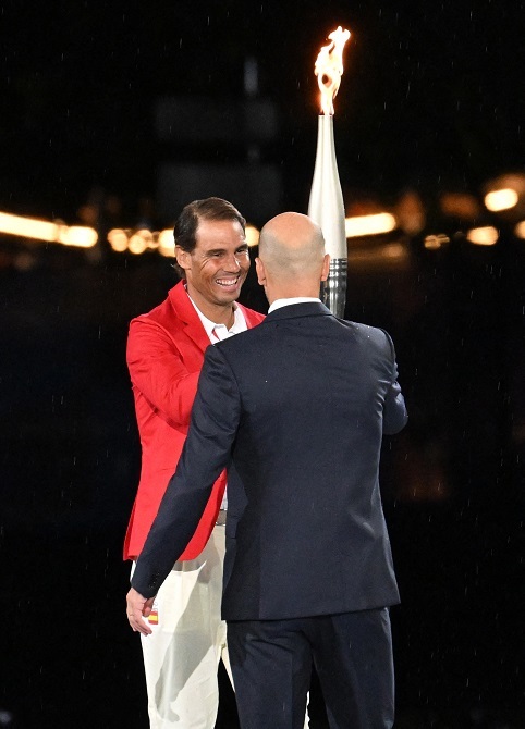 El exfutbolista francés Zinedine Zidane (dcha.) entrega una antorcha olímpica al tenista español Rafael Nadal durante la ceremonia de inauguración de los Juegos Olímpicos de París 2024 en la Place du Trocadero el 26 de julio de 2024 – PHOTO/Miho Ikeya/Yomiuri/The Yomiuri Shimbun vía AFP