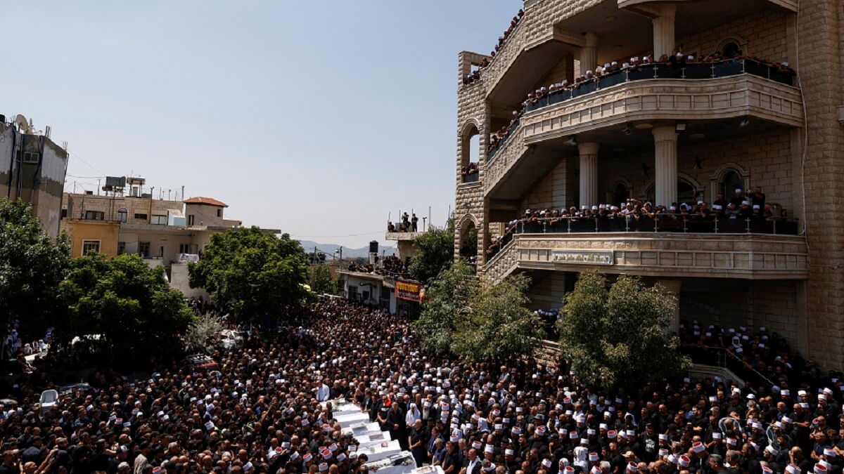 Ancianos drusos y dolientes rodean los ataúdes de 10 de las 12 personas muertas en un ataque con cohetes desde Líbano un día antes, durante un funeral multitudinario en la ciudad drusa de Majdal Shams, en los Altos del Golán anexionados por Israel, el 28 de julio de 2024 – PHOTO/Jalaa MAREY/AFP