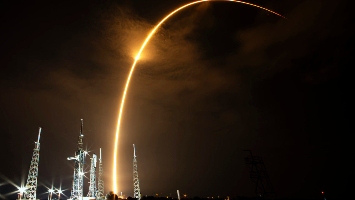 El primer Falcón 9 en pleno vuelo de ascenso desde Cabo Cañaveral en la madrugada del 27 de julio. Otro permanece en su rampa en tierra, a la espera del momento de su despegue - PHOTO/SpaceX