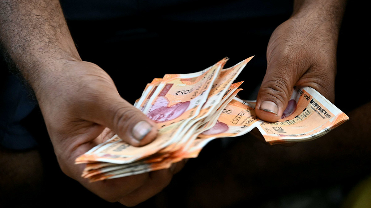 Un vendedor cuenta billetes de rupias indias en un puesto callejero en Mumbai - AFP/ INDRANIL MUKHERJEE
