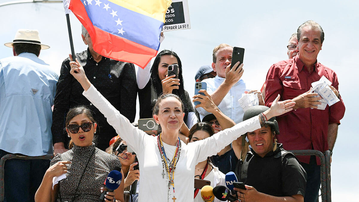 La líder opositora venezolana María Corina Machado (C) sostiene una bandera nacional sobre un camión durante una protesta convocada por la oposición para que se reconozca la victoria electoral, en Caracas el 17 de agosto de 2024 - AFP/FEDERICO PARRA