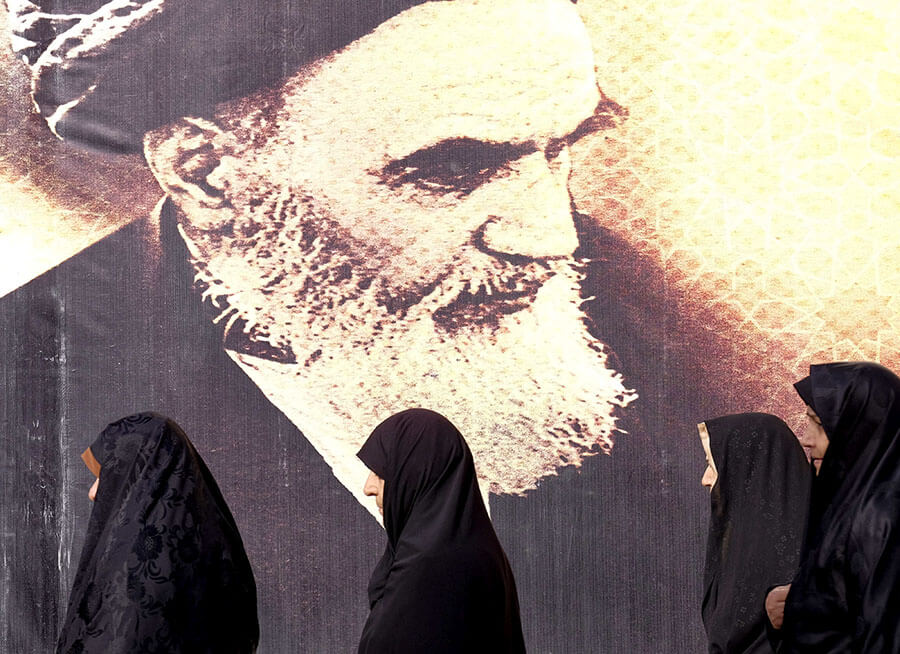 <p> Mujeres iraníes pasan junto a un cartel del difunto líder iraní, el ayatolá Ruhollah Jomeini, durante la ceremonia de aniversario de la Revolución Islámica de Irán en el cementerio Behesht Zahra, al sur de Teherán - REUTERS/RAHEB HOMAVANDI </p>