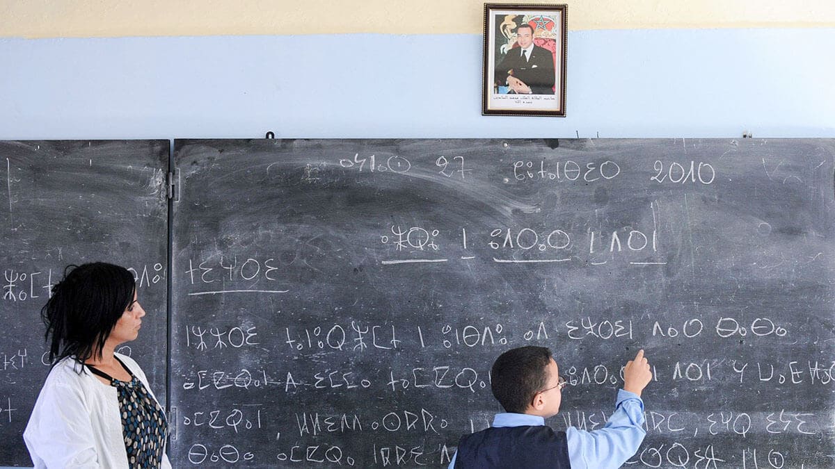 Una maestra de escuela ayuda a un alumno a leer un texto en amazigh, una lengua antigua de Raba - AFP/ ABDELHAK SENNA