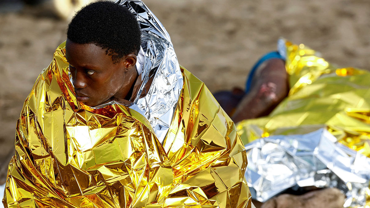 <p>Dos migrantes descansan en la arena tras llegar en una patera de fibra a la playa de Las Burras en San Agustín, en la isla de Gran Canaria, España, el 19 de julio de 2024 - REUTERS/ BORJA SUÁREZ</p>