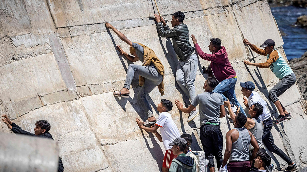 Fotografía de archivo, migrantes escalan un dique en la ciudad norteña de Fnideq después de intentar cruzar la frontera de Marruecos al enclave español de Ceuta en el norte de África - AFP/FADEL SENNA