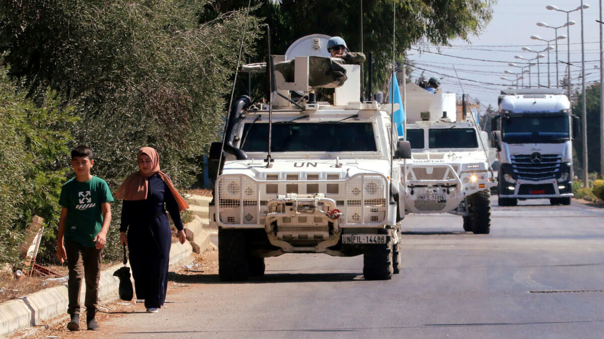 La gente camina cerca de los vehículos de las fuerzas de paz de la ONU (FPNUL) en Marjayoun, cerca de la frontera con Israel, en el sur del Líbano, el 9 de agosto de 2024 - REUTERS / KARAMALLAH