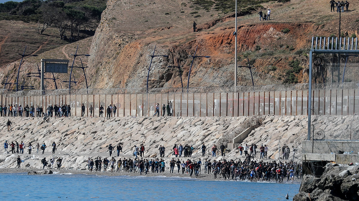 <p>Los migrantes corren hacia la valla que separa a Marruecos de España, después de que miles de migrantes cruzaran a nado la frontera, en Ceuta, España, el 19 de mayo de 2021 - REUTERS/ JON NAZCA</p>