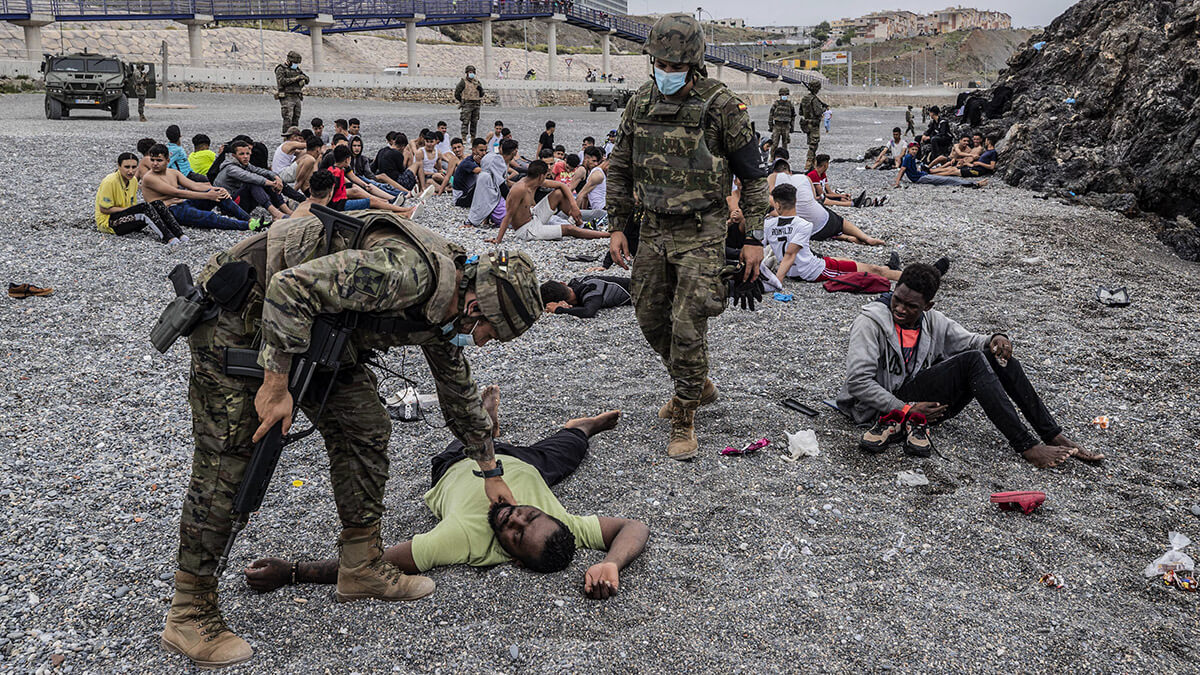 <p> Un migrante es asistido por soldados del Ejército español cerca de la frontera de Marruecos y España, en el enclave español de Ceuta, el martes 18 de mayo de 2021 - AP/BERNAT ARMANQUE</p>