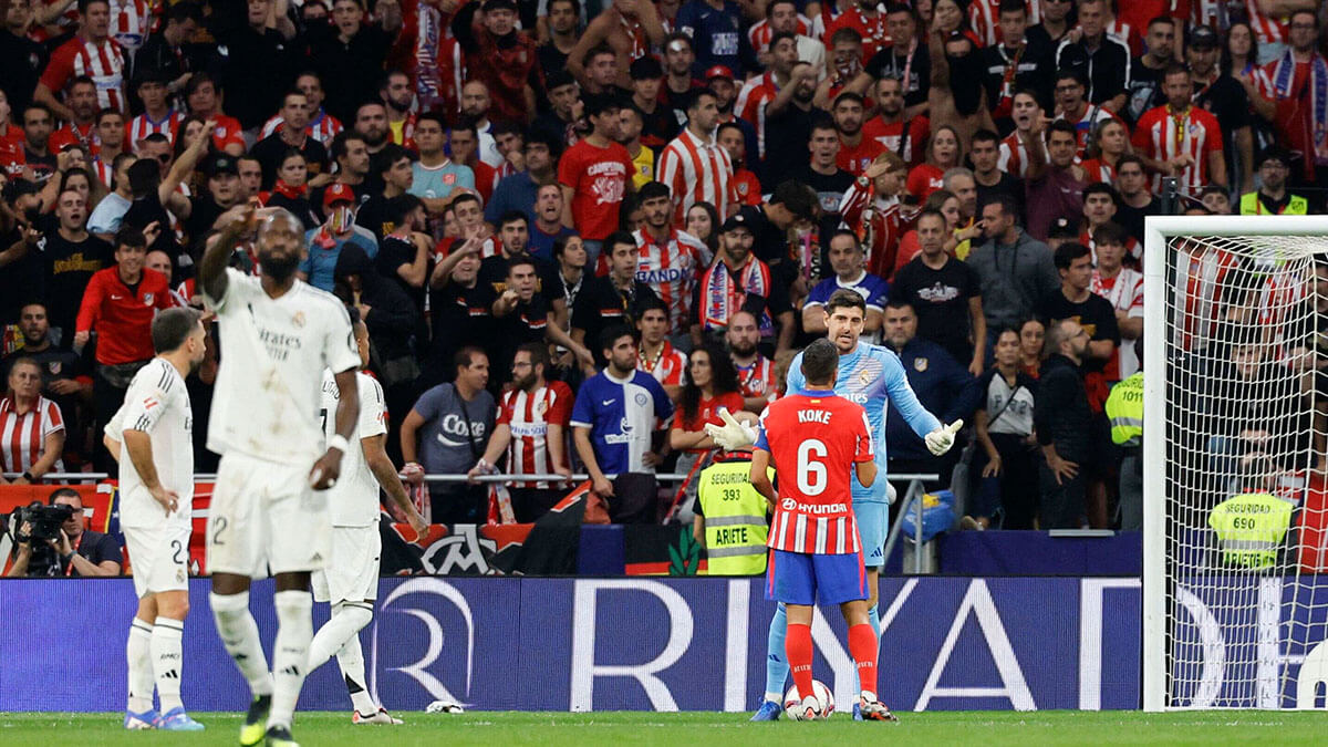 <p>Thibaut Courtois después de que los aficionados del Atlético de Madrid lanzaran objetos al campo tras el gol del defensa brasileño Eder Militao durante el partido de fútbol de la Liga española entre el Club Atlético de Madrid y el Real Madrid CF en el estadio Metropolitano de Madrid el 29 de septiembre de 2024 - AFP/ OSCAR DEL POZO </p>