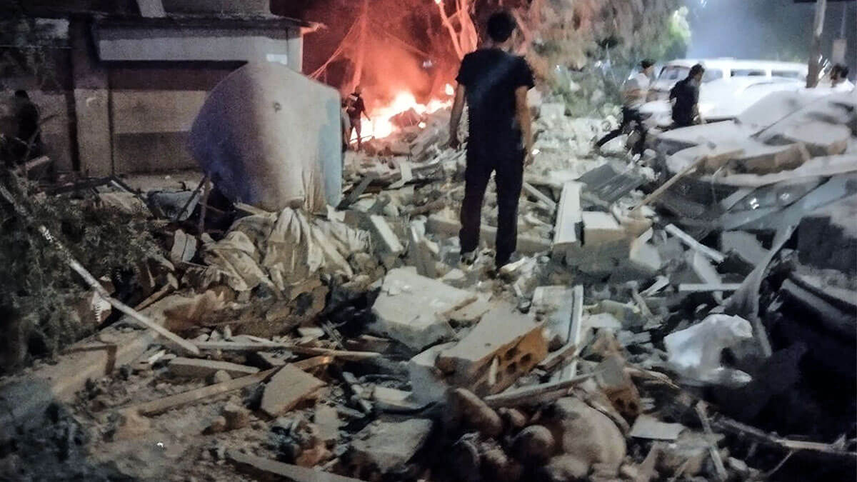 La gente se reúne junto a vehículos dañados en el lugar de un supuesto ataque aéreo israelí contra un edificio residencial, donde se dice que se reúnen miembros de alto rango del Cuerpo de la Guardia Revolucionaria Islámica de Irán (CGRI) y el Hezbolá libanés, en el suburbio de Mazzeh, en las afueras occidentales de la capital de Siria, Damasco, el 8 de octubre de 2024 - PHOTO/ AFP