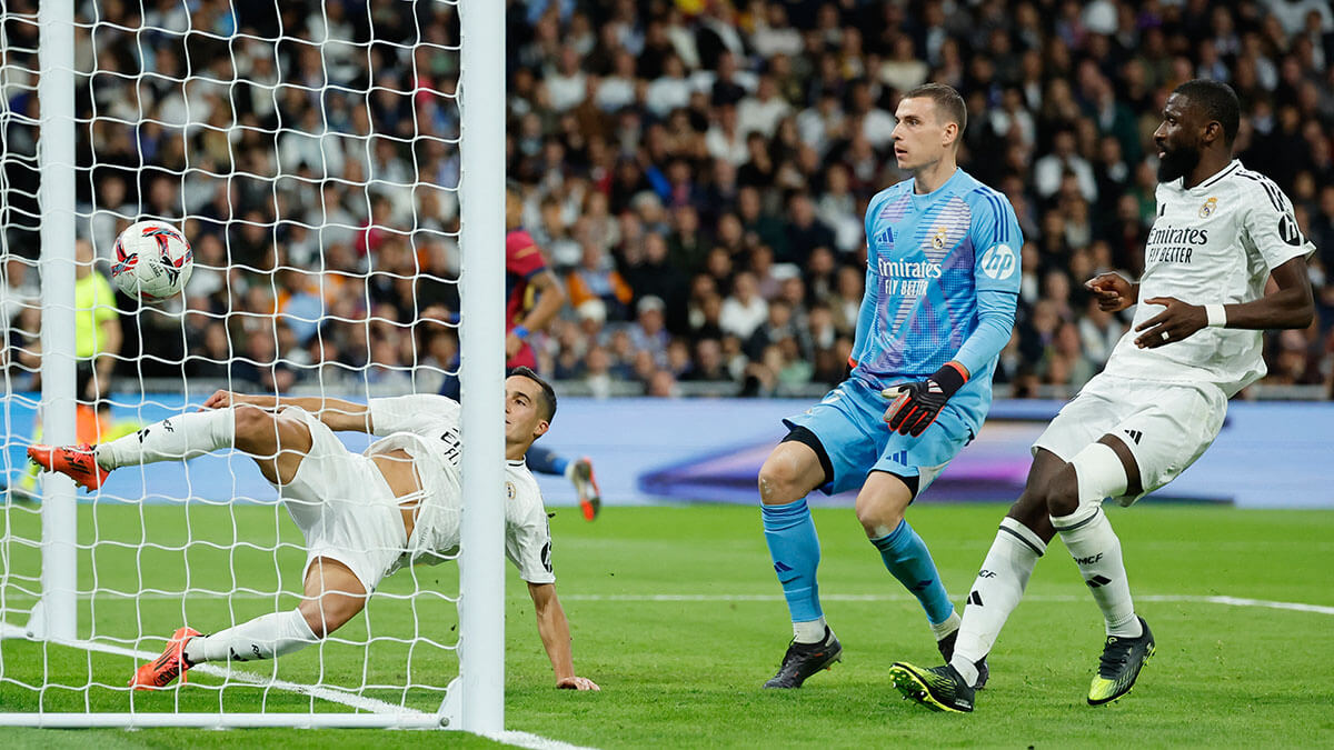 <p>El defensa español del Real Madrid Lucas Vázquez no logra salvar el gol del delantero brasileño del Barcelona Raphinha durante el partido de fútbol de la Liga española entre el Real Madrid CF y el FC Barcelona en el estadio Santiago Bernabéu de Madrid el 26 de octubre de 2024 - AFP/OSCAR DEL POZO </p>