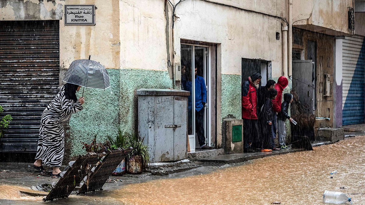 <p>La gente se refugia de la lluvia en una calle inundada durante una tormenta en la ciudad de Fnideq, en el norte de Marruecos, el 5 de marzo de 2021 - AFP/ FADEL SENNA </p>
